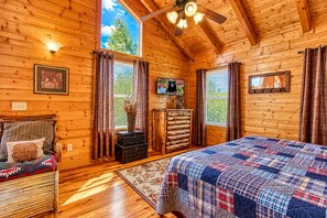 A cozy cabin bedroom with a bed, a dresser, a chair, and a television. - Big Sky, Breathtaking Mtn View, Free Attraction Tickets, Pool Table, Hot Tub!!! (Sevierville)