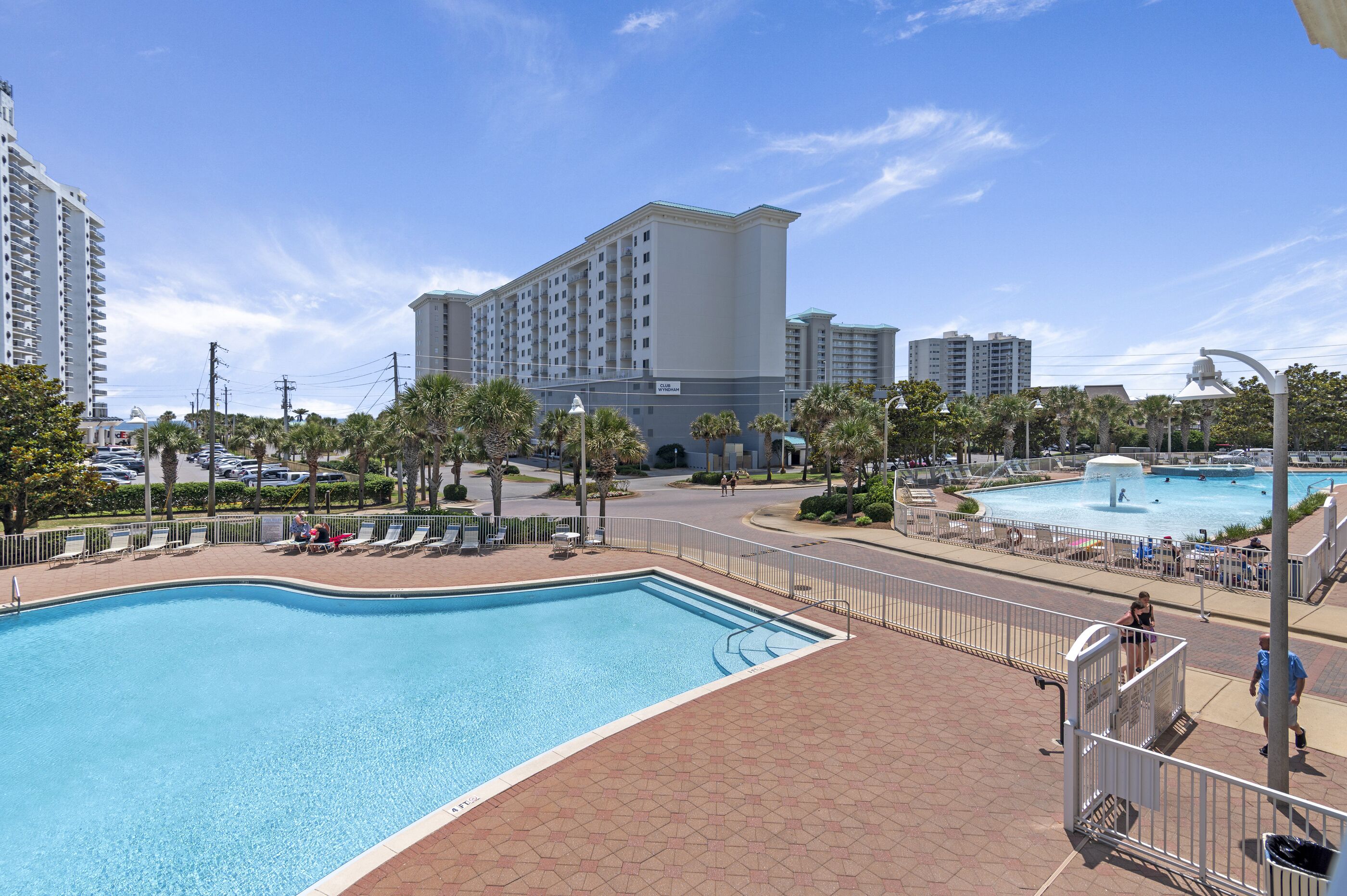 A swimming pool area with a view of high-rise buildings, a fountain, and a pedestrian walkway.