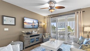 A living room with a white coffee table, grey sofa, and a TV on the wall.