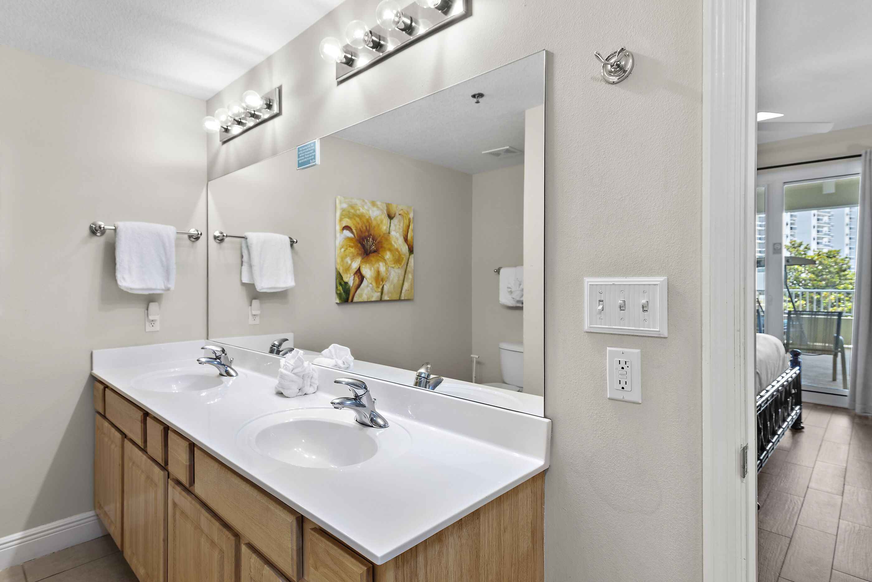 Un baño con dos lavamanos, un espejo grande y un cuadro de flores.