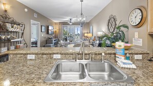A kitchen with granite countertops, a double sink, and a chandelier.