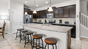 A modern kitchen with dark cabinets, a granite island, bar stools, and pendant lighting. - Lazy River! VALUE PRICED! Waterpark Adventure Resort Near Disney! 2018 (Kissimmee)