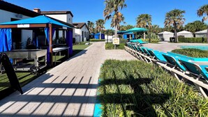 A poolside area with lounge chairs, a barbecue setup, and a building with a sign indicating an exit. - Lazy River! VALUE PRICED! Waterpark Adventure Resort Near Disney! 2018 (Kissimmee)