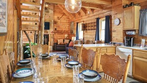 L’intérieur d’un chalet en bois, avec une table à manger dressée pour quatre personnes, entourée de chaises en bois.
