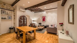 A spacious living room with a wooden dining table, a sofa, and a fireplace. - Pebble Loft 1 bedroom apartment VRBO (Nice)