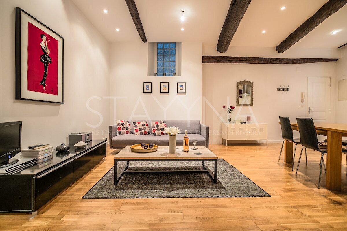 Een moderne woonkamer met een bank, salontafel en televisie. Er is een eethoek met een tafel en stoelen.