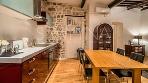 A kitchen with a stone wall, wooden table, and chairs. - Pebble Loft 1 bedroom apartment VRBO (Nice)