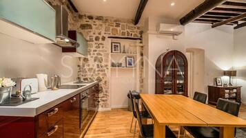 Une cuisine avec un mur en pierre, une table en bois et des chaises.