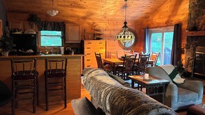 Interior acogedor de una cabaña con comedor de madera, una cocina con refrigerador y una chimenea.