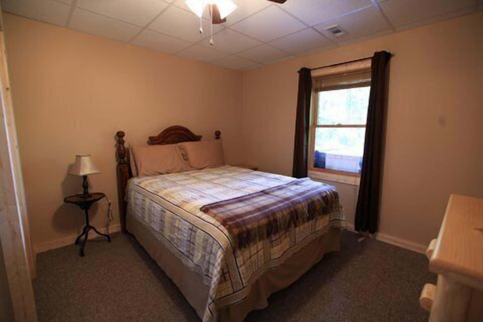 Une chambre à coucher avec un lit, une table de chevet, une lampe et une fenêtre.