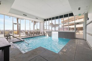 An indoor swimming pool with clear glass walls, a view of palm trees, and a rooftop terrace. - Seawind 608 by Liquid Life (Gulf Shores)