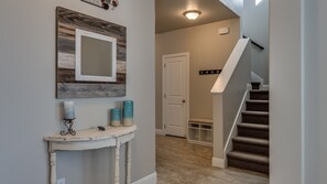 A hallway with a white console table, a mirror, and a door leading to a staircase.