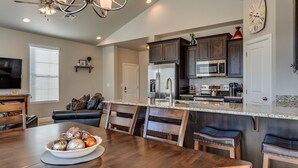 A modern kitchen with dark wood cabinets, stainless steel appliances, and a granite countertop.