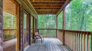 A wooden deck with a bench, surrounded by a wooden railing, overlooking a forested area. - Awesome Honey Bear, “Cozy Cabin Retreat in the Smokies – Comfort & Fun for All”! (Sevierville)
