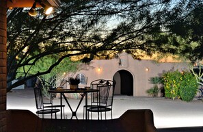An outdoor seating area with a table and chairs, a brick wall, and a decorative metal gate.