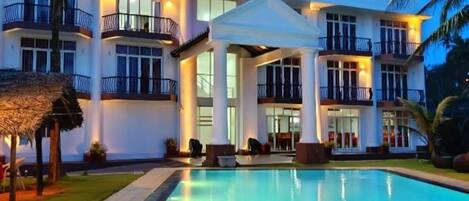 A resort with a swimming pool, multiple balconies, and a well-lit facade.