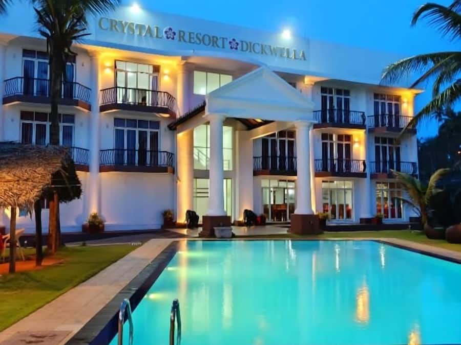 A resort with a swimming pool, multiple balconies, and a well-lit facade.
