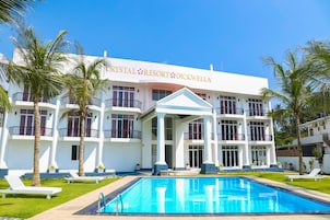 Un resort con piscina, palmeras y un edificio blanco con balcones.