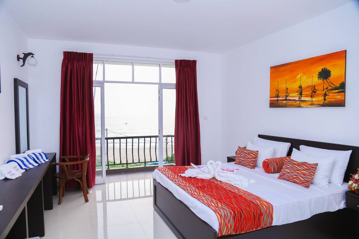 A hotel room with a bed, a desk, a chair, and a painting on the wall.