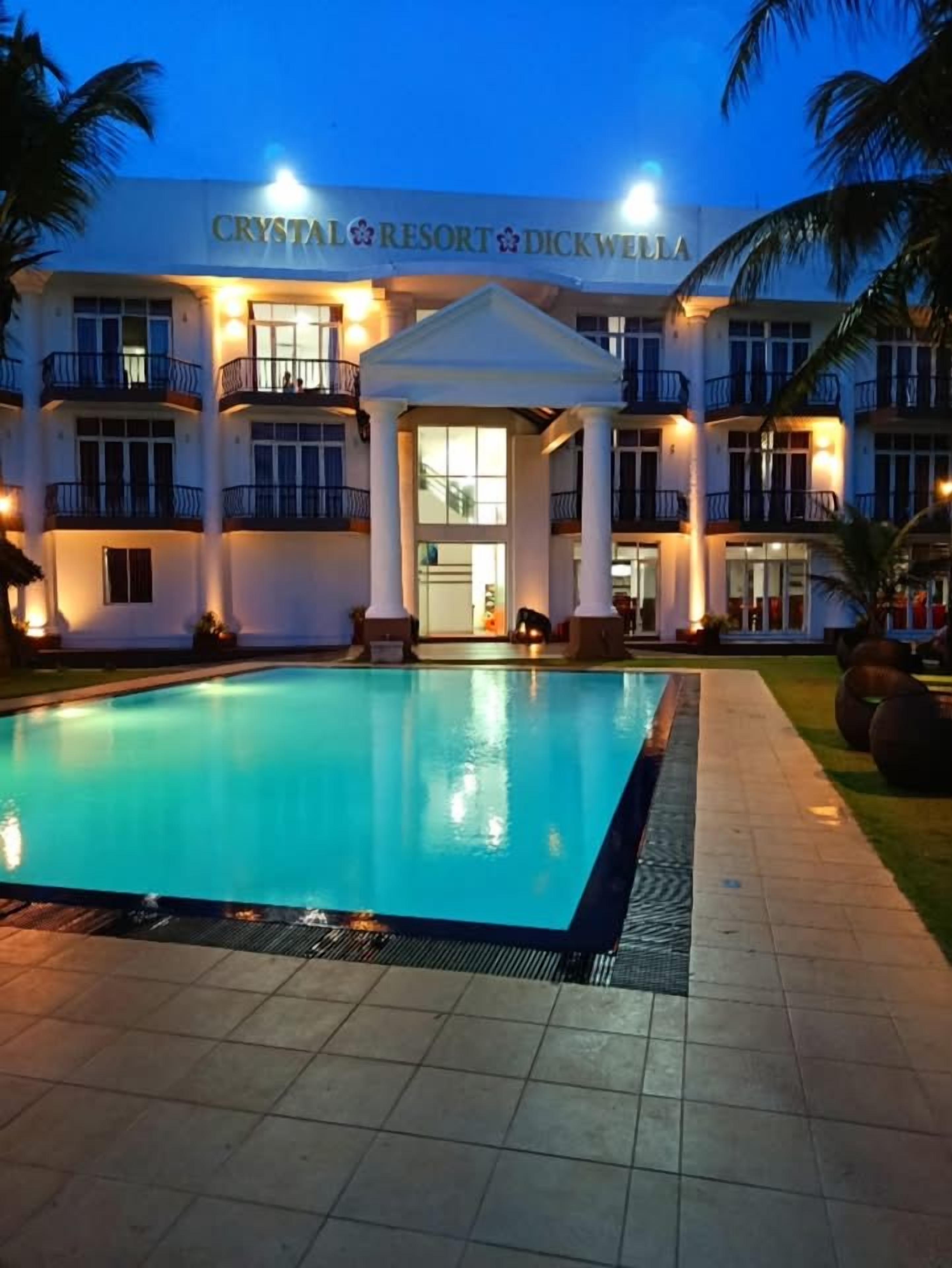 Um hotel chamado 'Crystal Resort & Dickwellia' com uma piscina à frente.