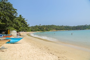 A beach with boats, a sandy shore, and a forested background.