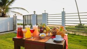 A breakfast table with drinks, fruits, and eggs on a terrace with a view of the sea. - Crystal Resort Dickwella (Dikwella)