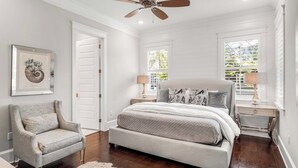 A bedroom with a bed, a chair, a ceiling fan, and two bedside tables with lamps.