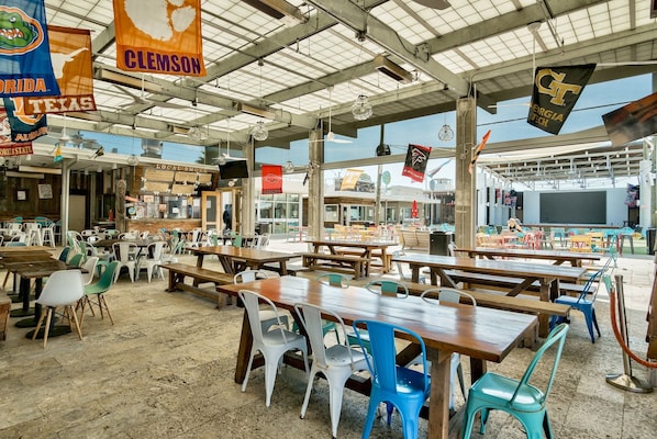 An outdoor dining area with multiple tables and chairs, surrounded by various flags.