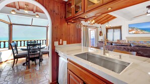 A kitchen with a large island, wooden cabinets, and a view of the ocean. - Remodeled 1B|1B Villa,Golf Cart, WIFI, Gorgeous Panoramic Ocean Views, golf cart (Avalon)