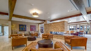 A spacious lobby with leather sofas, a stone wall, and a fireplace.