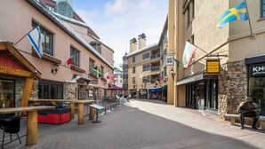 A cobblestone street lined with buildings featuring outdoor seating areas and flags.