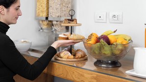 A person holding a tray with pastries and a bowl of fruit on a counter. - Hotel la Scala (Florence)