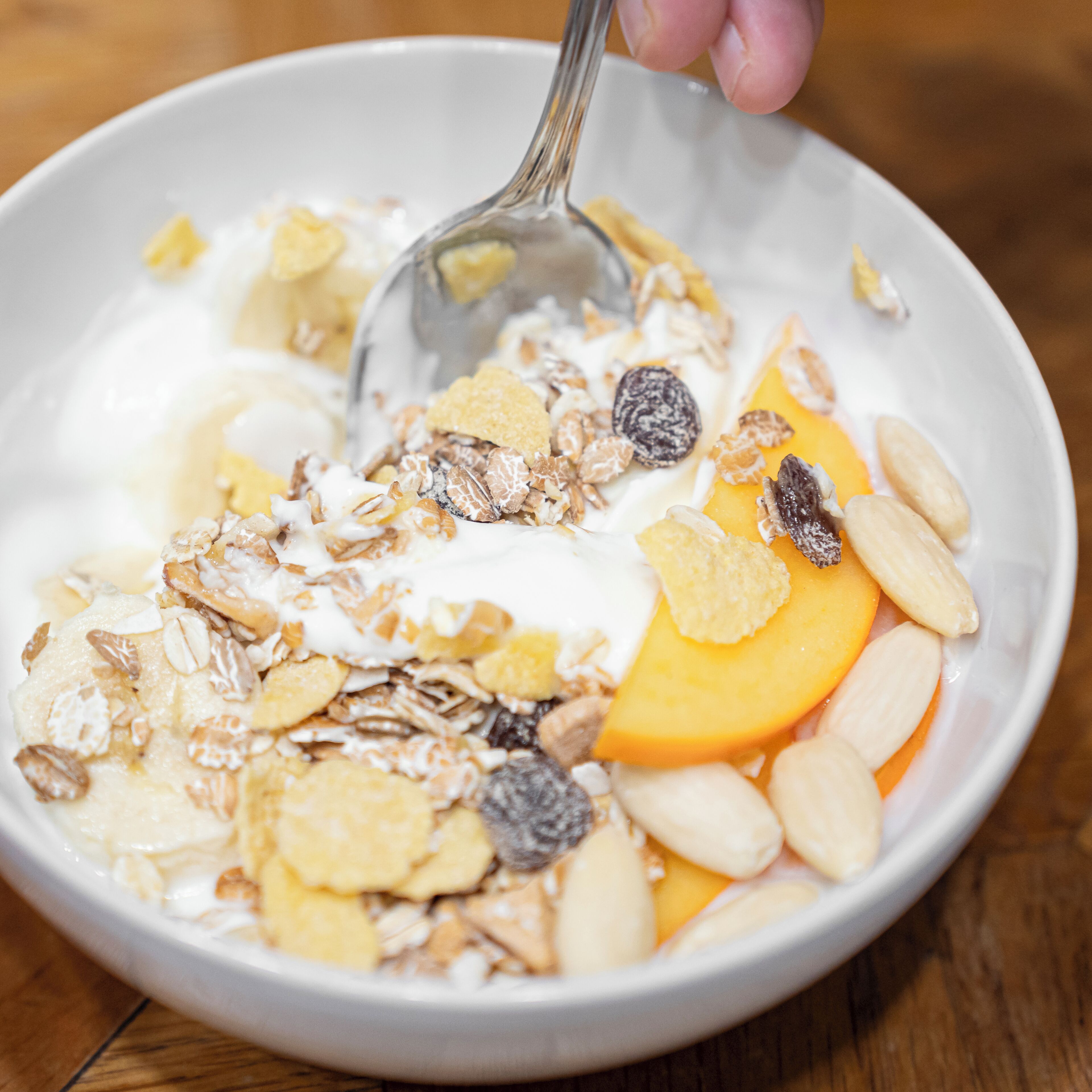 A bowl of cereal with milk, granola, and fruit.