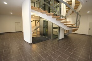 A modern interior with a spiral staircase, a glass door entrance, and a tiled floor. - Käptn Brass App 8 - Käpt`n Brass App. 8 (Dierhagen)