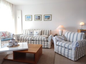 A living room with striped sofas, a wooden coffee table, and a lamp. - Käptn Brass App 8 - Käpt`n Brass App. 8 (Dierhagen)