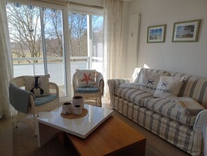 A living room with a sofa, two chairs, a coffee table, and a view through large windows. - Käptn Brass App 8 - Käpt`n Brass App. 8 (Dierhagen)