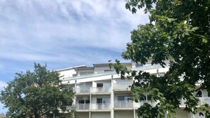 A multi-story building with balconies, a grassy lawn, and trees. - Käptn Brass App 8 - Käpt`n Brass App. 8 (Dierhagen)