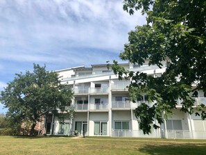 A multi-story building with balconies, a grassy lawn, and trees. - Käptn Brass App 8 - Käpt`n Brass App. 8 (Dierhagen)
