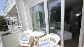A balcony with wicker chairs and a table, a sliding glass door leading to an interior space with a sofa and a small table. - Käptn Brass App 8 - Käpt`n Brass App. 8 (Dierhagen)