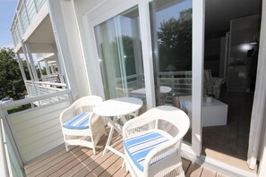 A balcony with wicker chairs and a table, a sliding glass door leading to an interior space with a sofa and a small table. - Käptn Brass App 8 - Käpt`n Brass App. 8 (Dierhagen)