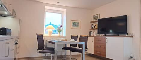 Una cocina moderna con una mesa de comedor, sillas, un televisor y una ventana con vistas.