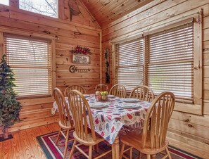 A wooden cabin interior with a dining table set for six, surrounded by wooden chairs. - Cub Crossing, Free Attraction Tickets, Hot Tub, Pool Table, WIFI!!! (Sevierville)