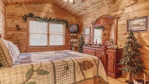 Une chambre chaleureuse dans un chalet en rondins, avec un lit, une commode et des décorations de Noël.
