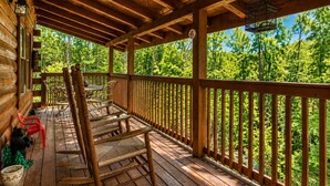 Une terrasse en bois avec une rambarde, une table et des chaises.