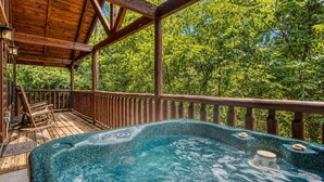 A hot tub on a wooden deck with a view of trees.