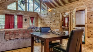 A cozy cabin interior with a dining area, a sofa, and a kitchen.