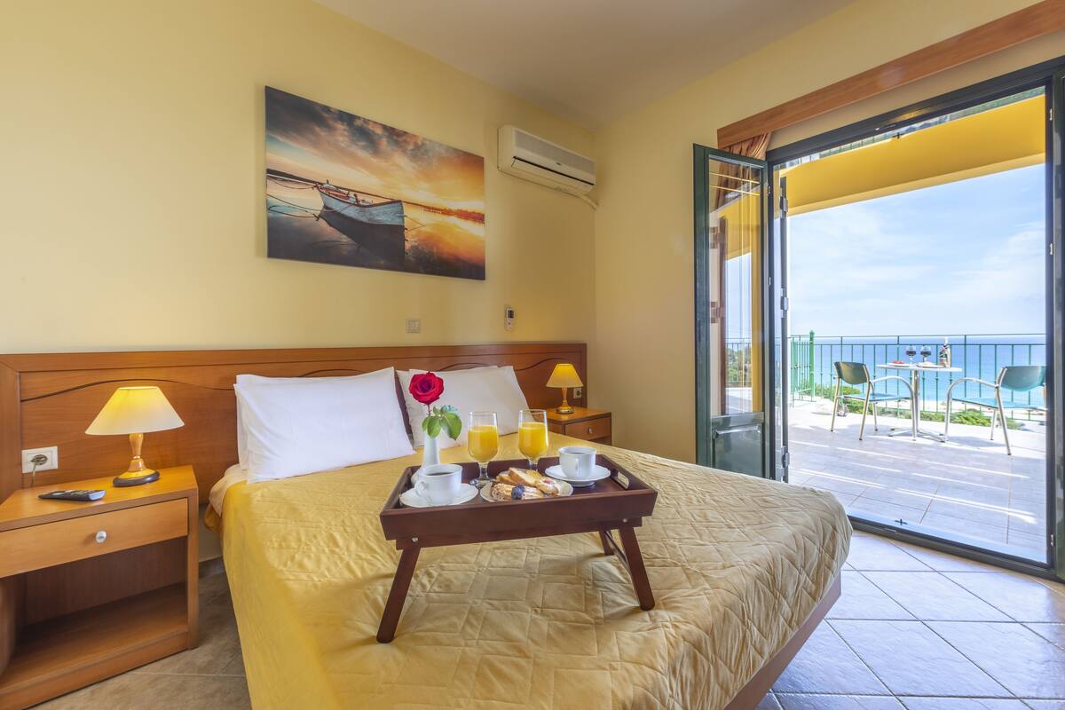 Ein Hotelzimmer mit einem Bett, einem Frühstücksbrett und einer Aussicht auf einen Balkon, sowie einem Gemälde an der Wand.