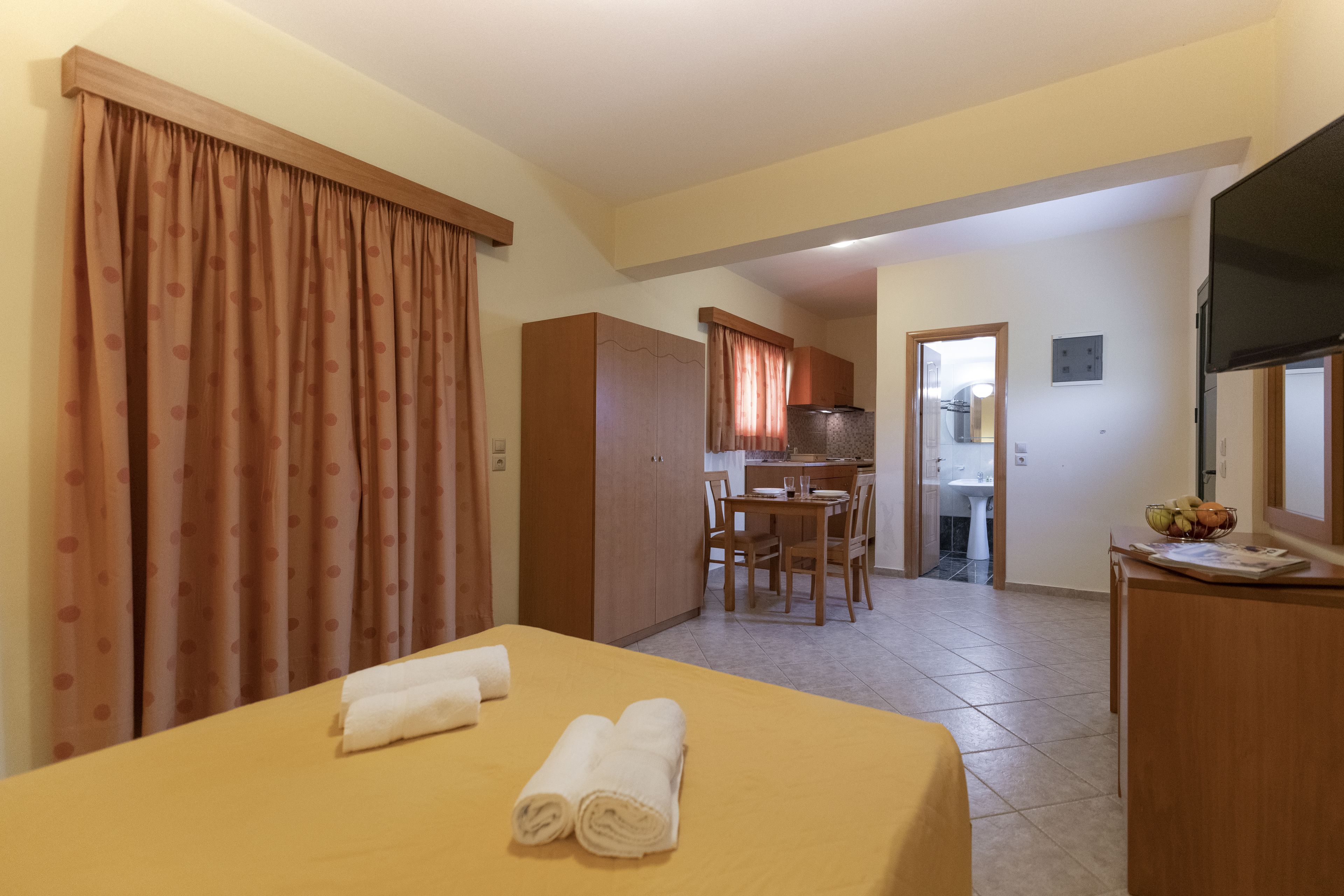A hotel room with a bed, a dining table, and a kitchen area.