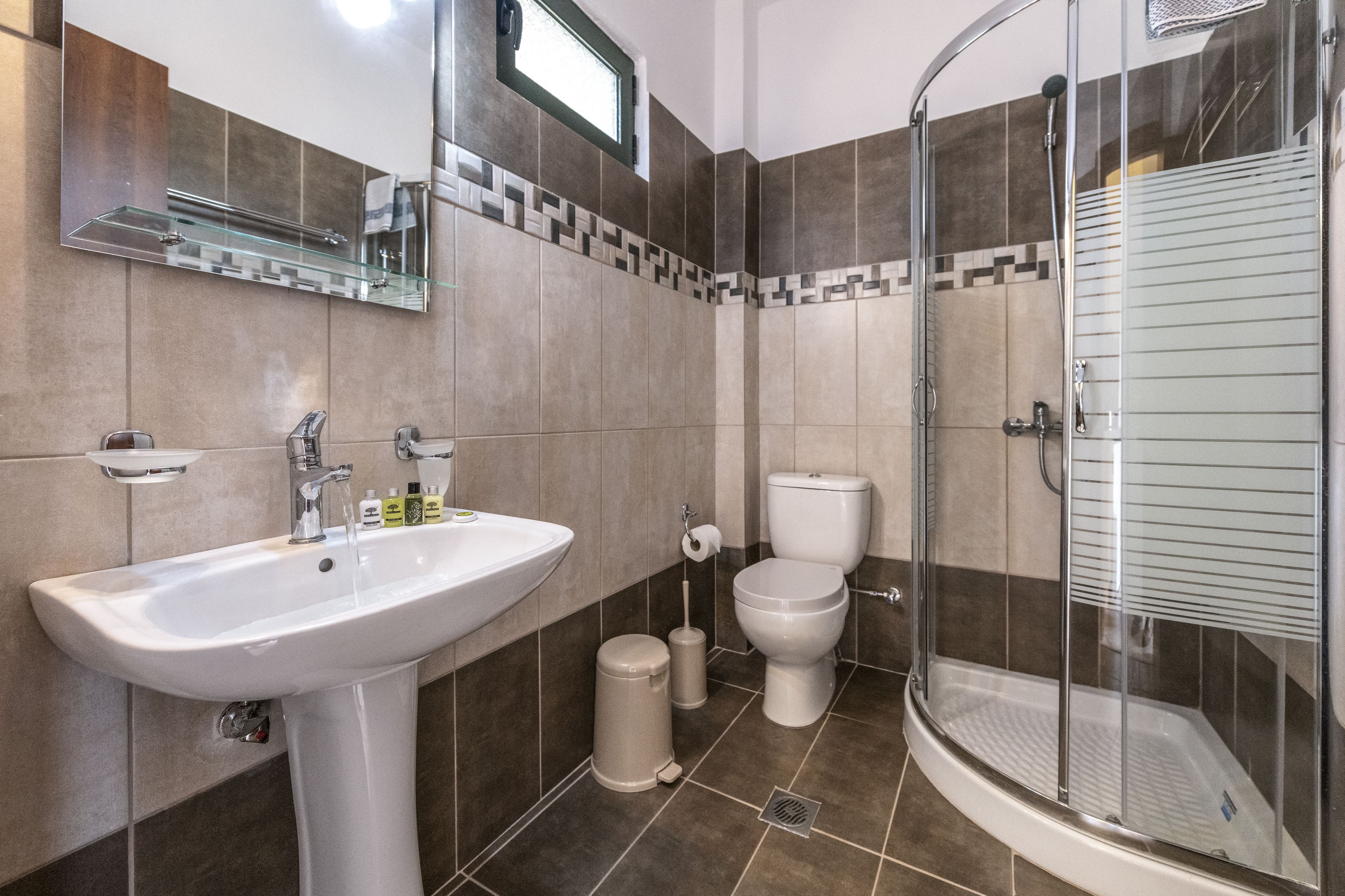 Un baño moderno con lavamanos, inodoro y ducha con mampara de vidrio.