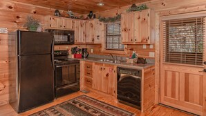 A wooden cabin kitchen with a refrigerator, stove, microwave, sink, and dishwasher. - Bearskin Romance- Free Attraction Tickets ,WIFI, Pool Table, Air Hockey, Hot Tub (Sevierville)